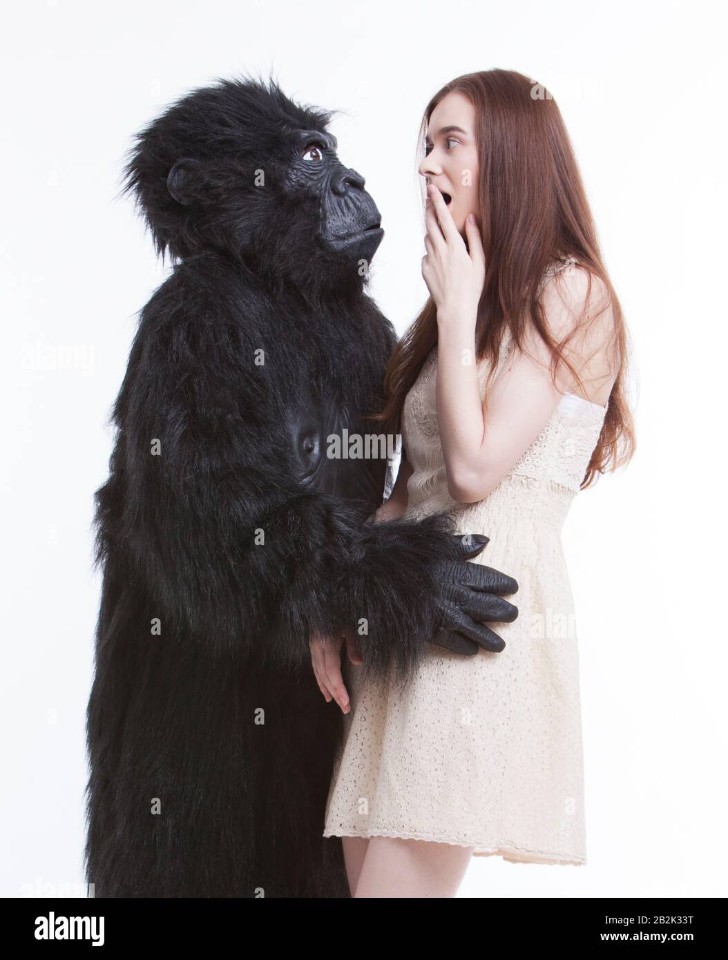 Man in gorilla costume hugging frightened young woman against white background Stock Photo