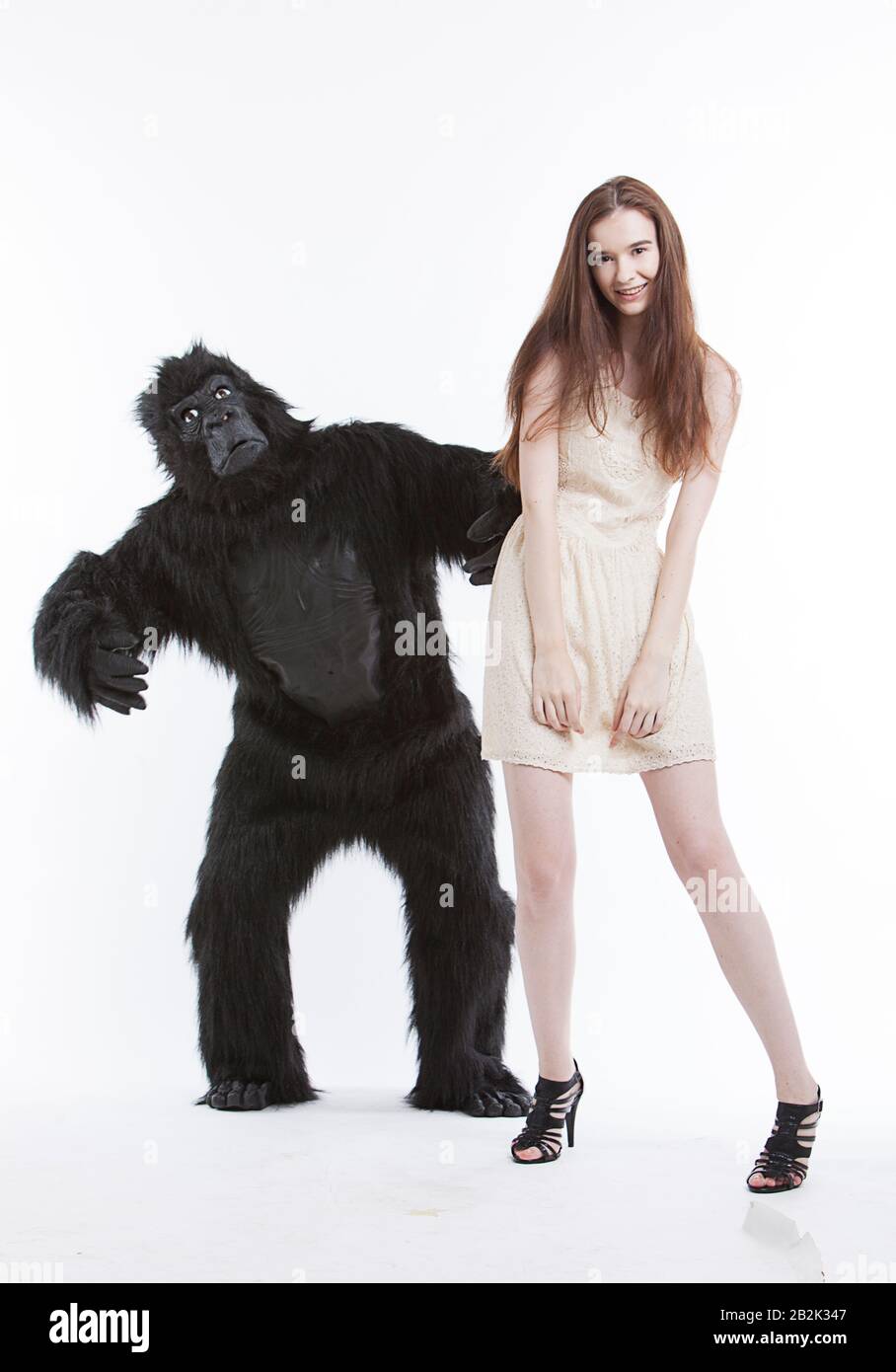 Portrait of smiling young woman with man in gorilla costume against white background Stock Photo