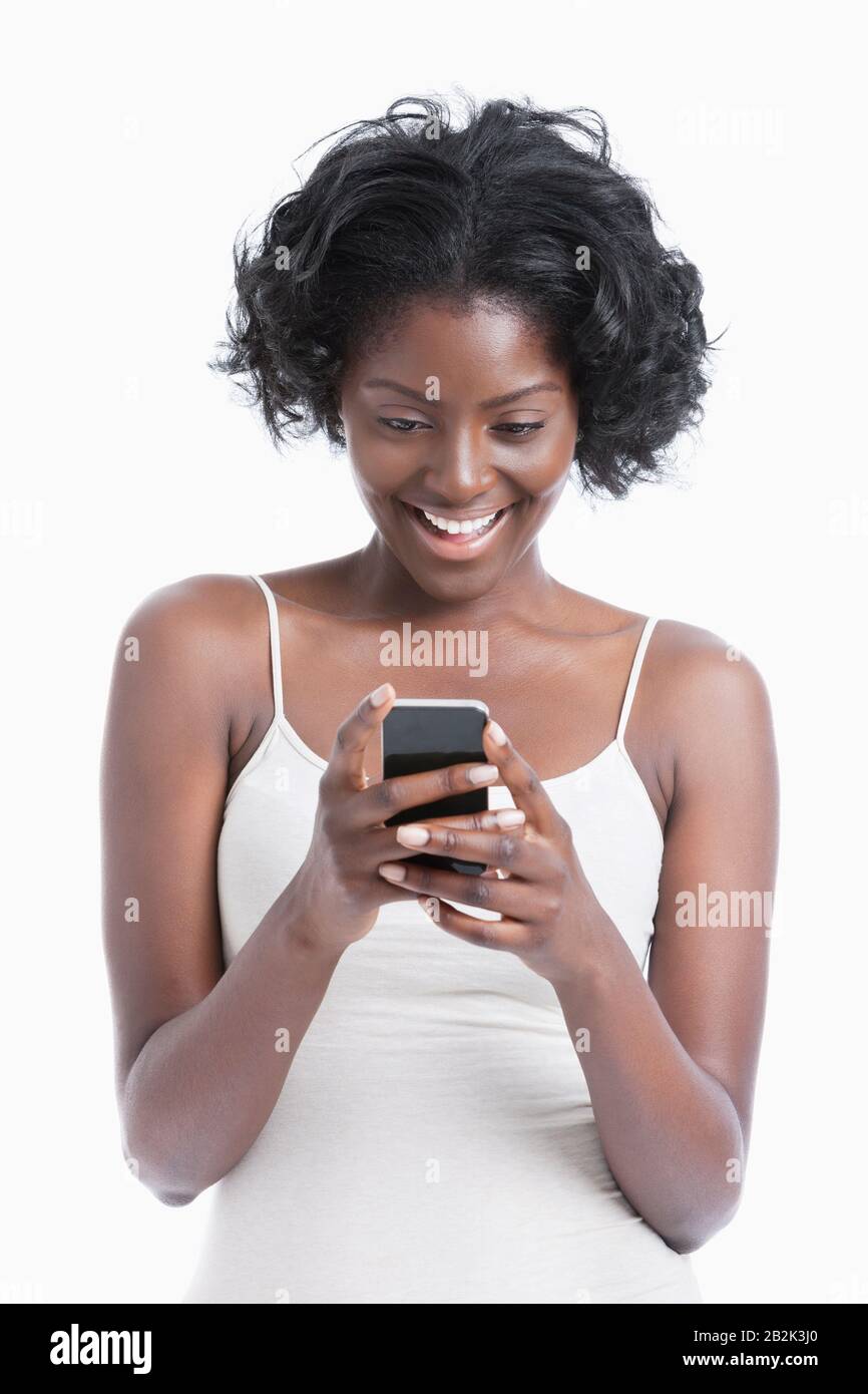 Happy young African American woman text messaging over white background ...