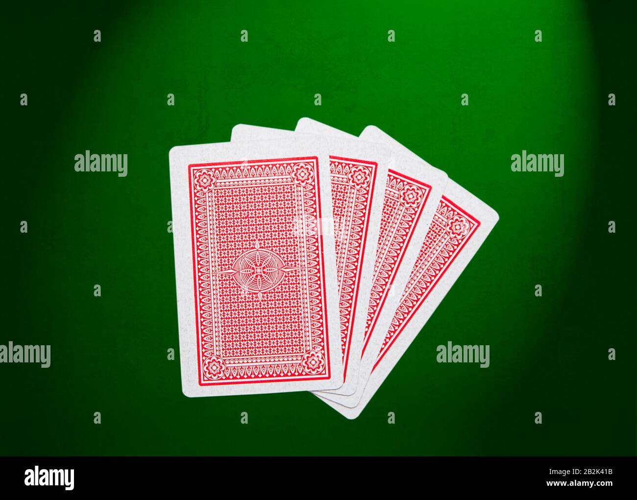 Four red cards on their front sitting on green felt Stock Photo
