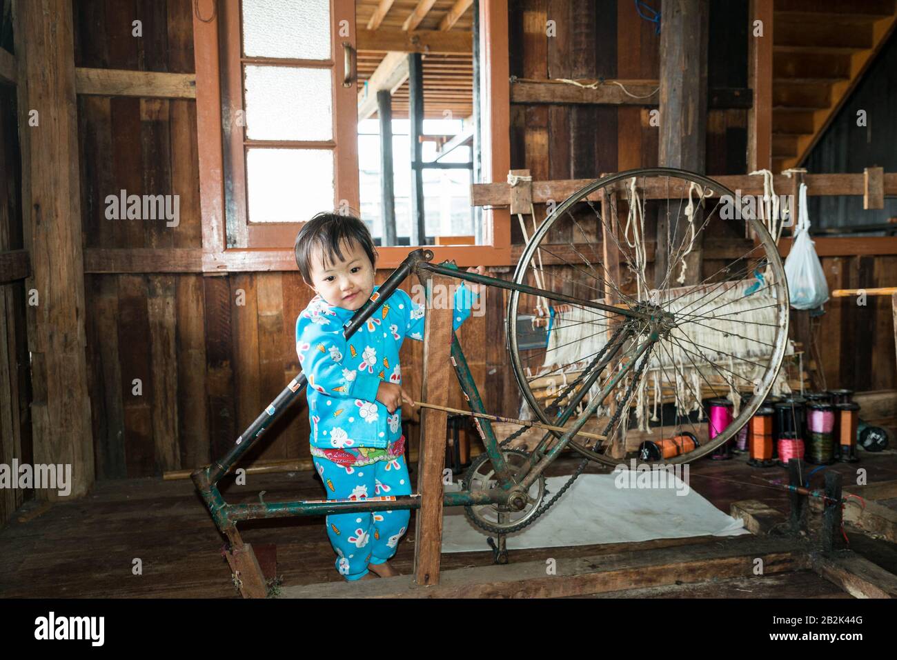 Child playing with a spinning wheel in Weaving factory on Inle Lake in