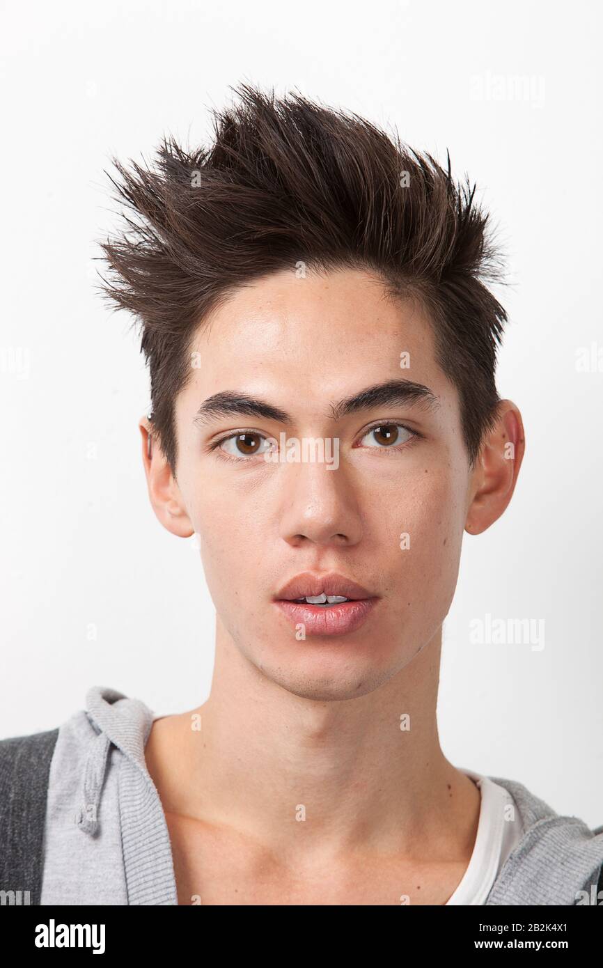 Portrait of young mixed race man with spiked hair against white background Stock Photo