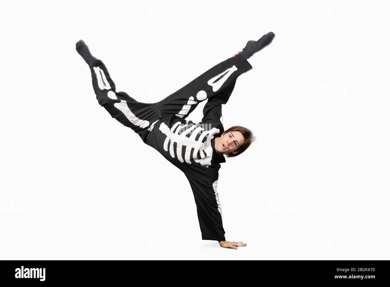 Young man in skeleton costume break dancing against white background Stock Photo