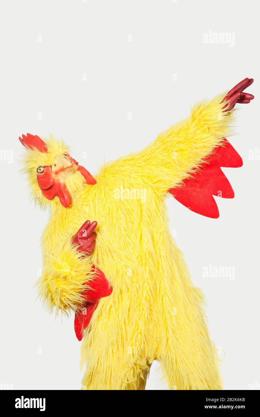 Playful young man in chicken suit against gray background Stock Photo