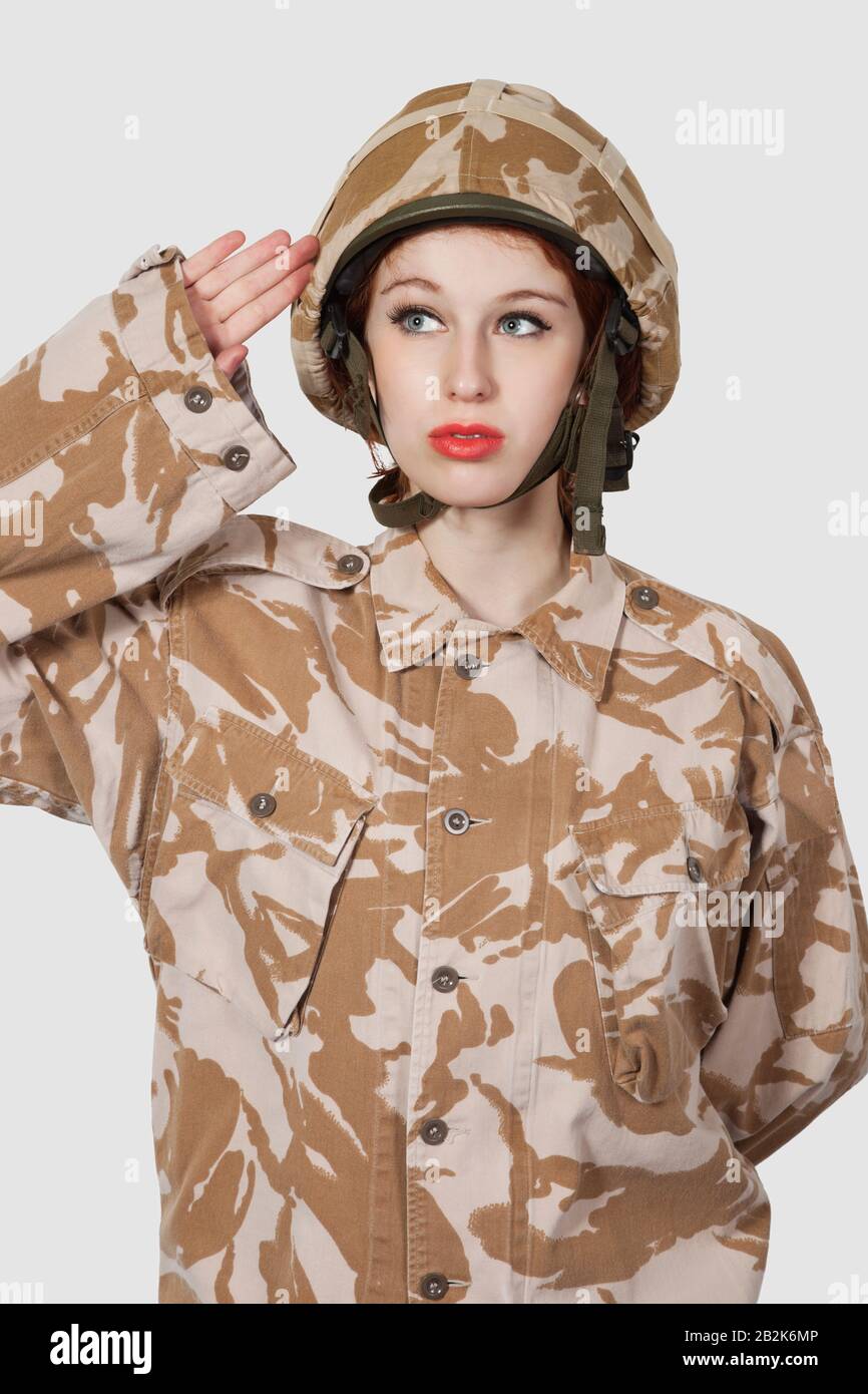 Young woman in military uniform saluting against gray background Stock ...
