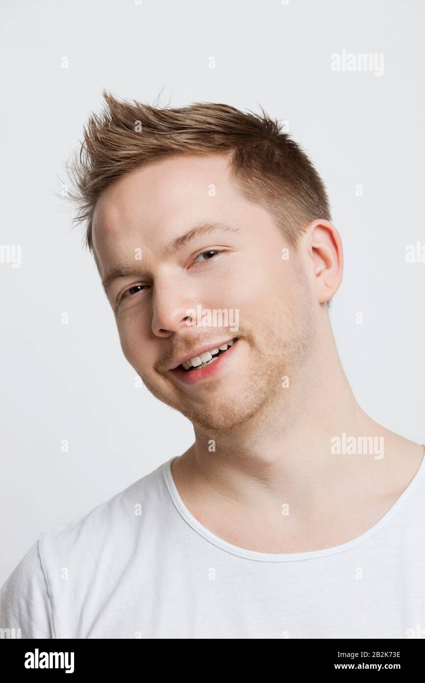 Portrait of young Caucasian man with spiked hair smiling against white background Stock Photo