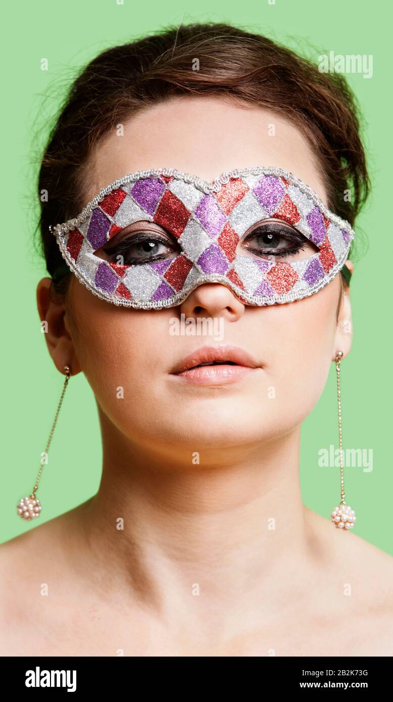 Portrait of beautiful young woman wearing eye mask against green background Stock Photo