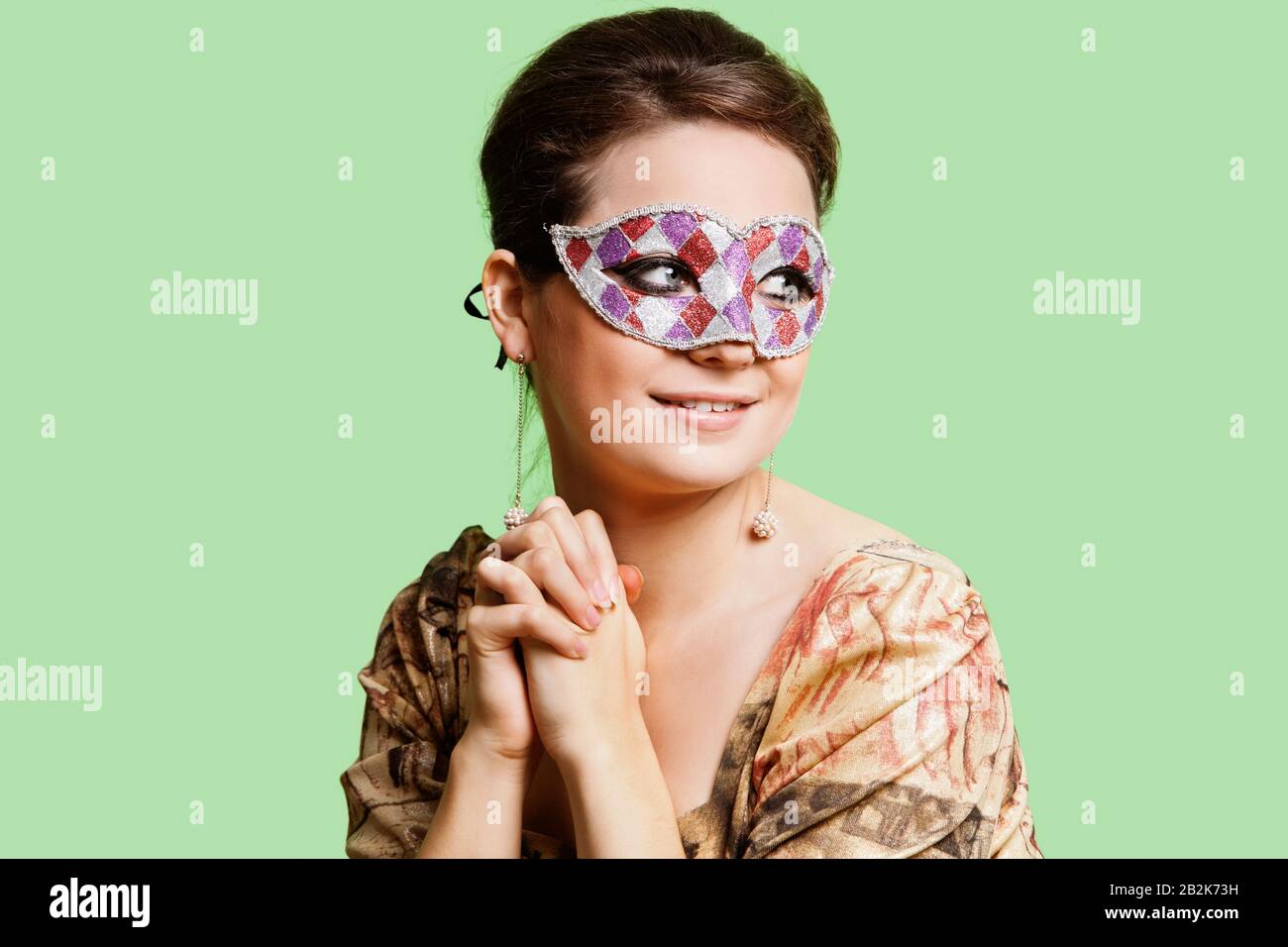 Portrait of beautiful young woman with eye mask day dreaming against green background Stock Photo