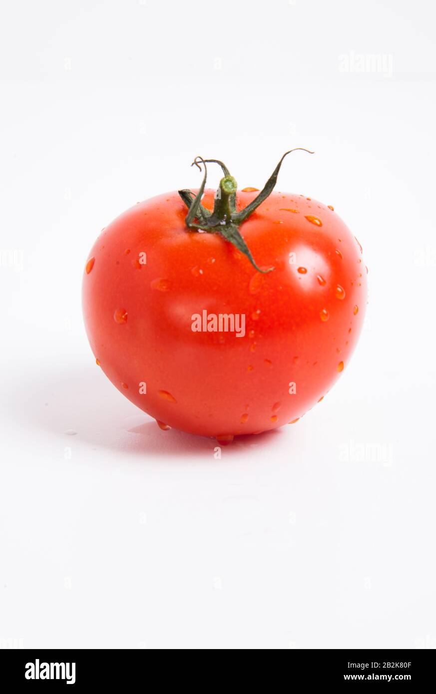 Close-up of fresh red tomato with water droplets over white background Stock Photo