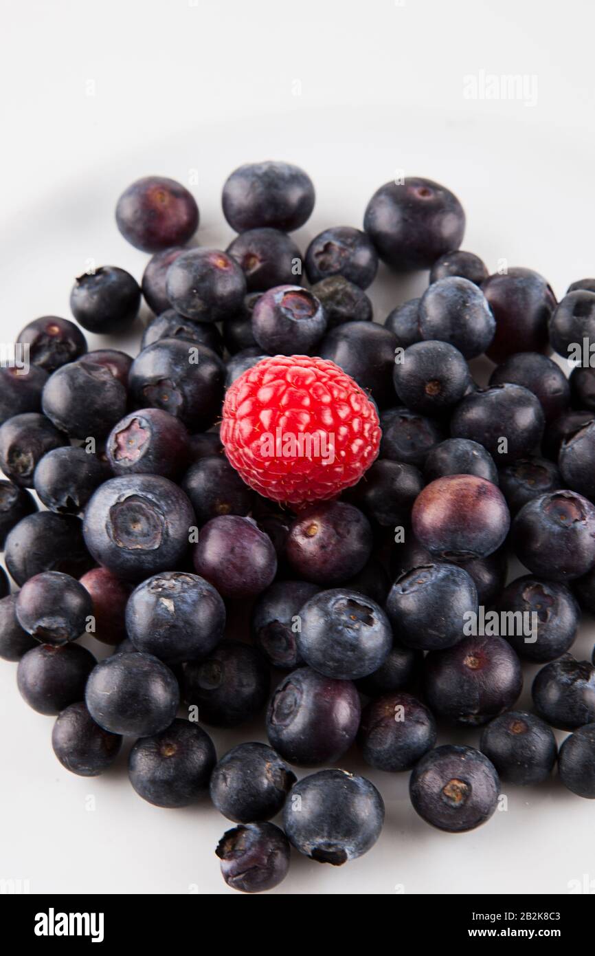 Close-up of raspberry over blueberries against white background Stock Photo