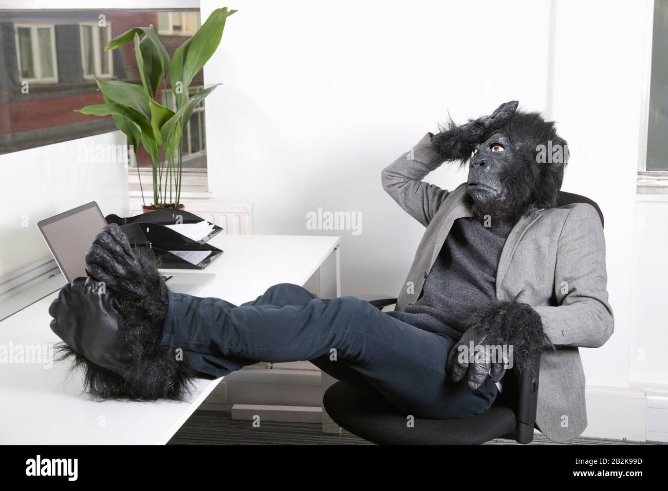 Thoughtful young man in gorilla costume resting at office Stock Photo