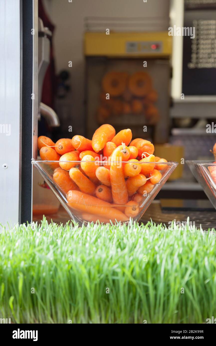Close-up of grass with container full of carrots Stock Photo