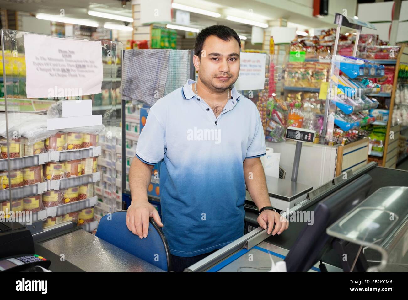 Portrait of male clerk standing at counter in grocery store Stock Photo