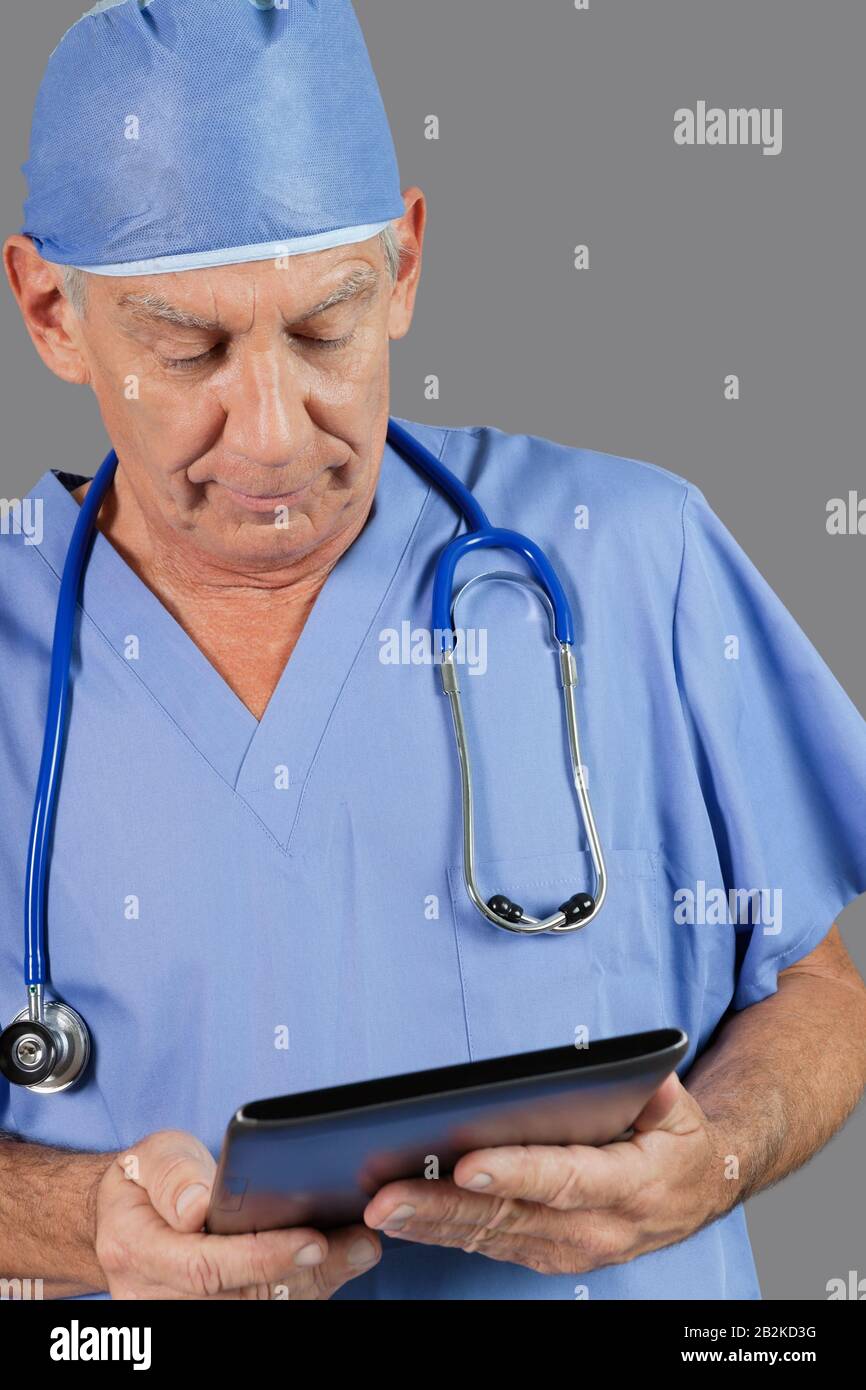 Senior male surgeon using tablet PC over gray background Stock Photo