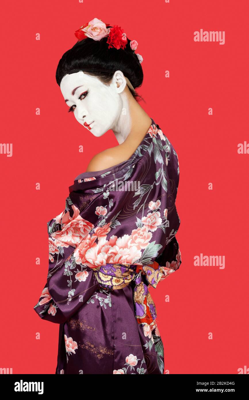 Portrait of Japanese woman in kimono standing over red background Stock Photo