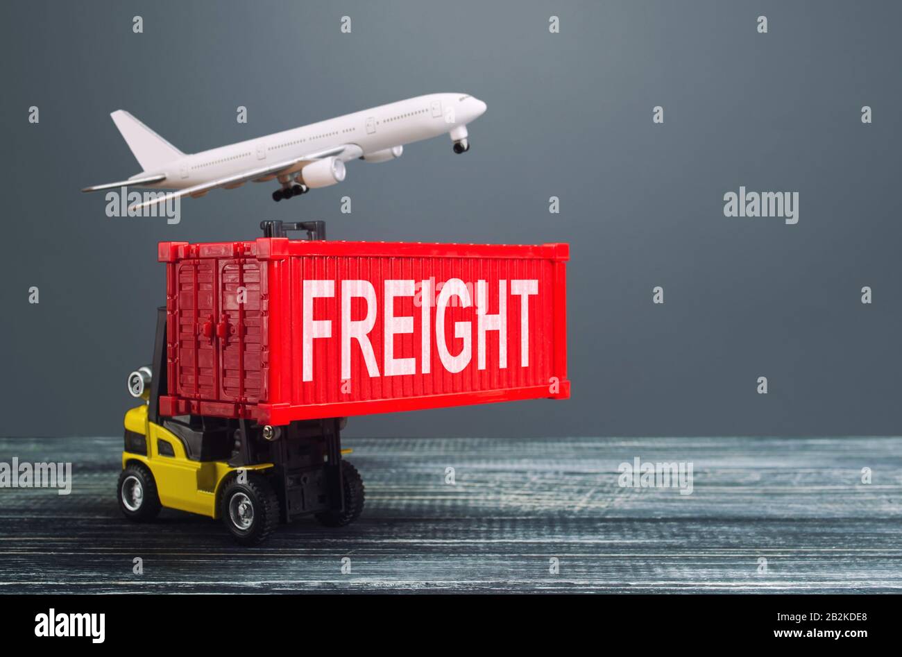 Yellow forklift carries red container and freight plane. International transportation logistics infrastructure, import export of goods products. Wareh Stock Photo