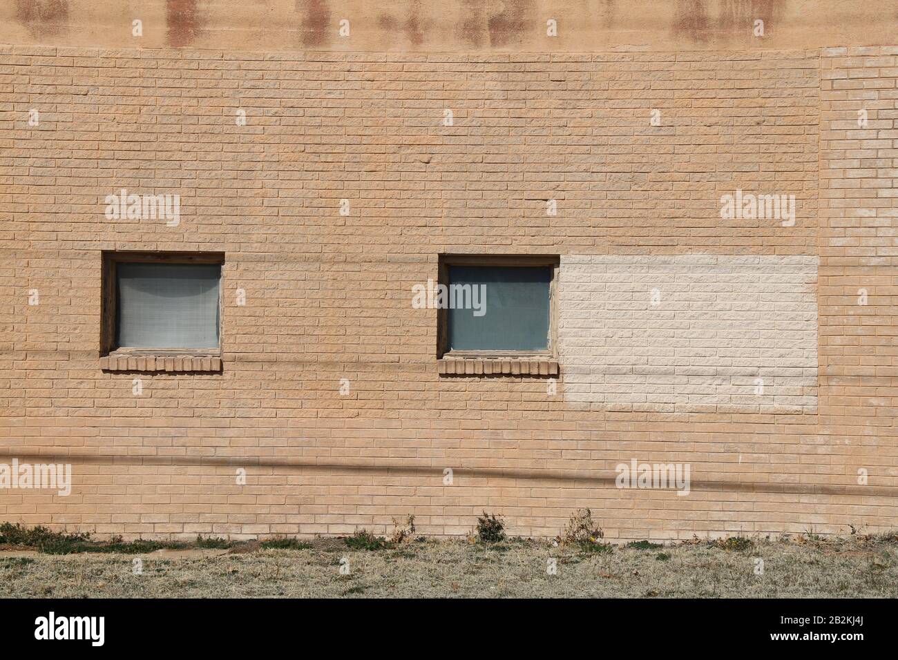 a pair of square vintage windows on the facade of a brown brick wall ...