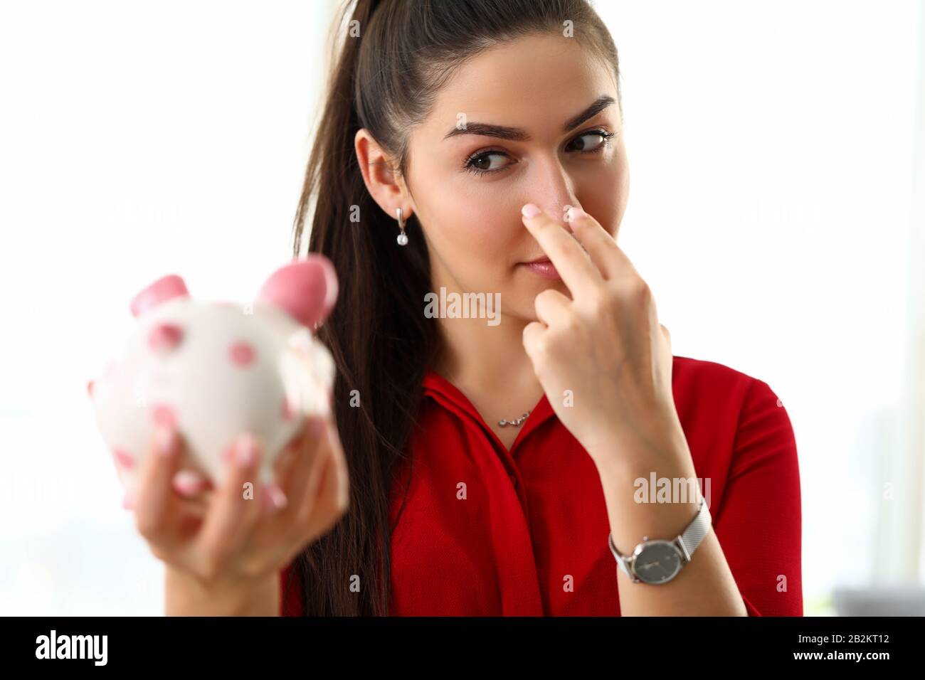 Smiling beautiful woman watching over bad and guilty piggybank Stock Photo