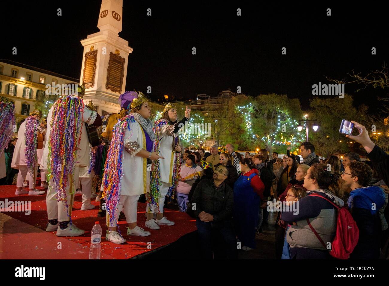 Satirical singers in fancy dress - comparsas and chirigotas - performing in Plaza de la Merced during the Málaga Carnival. Stock Photo