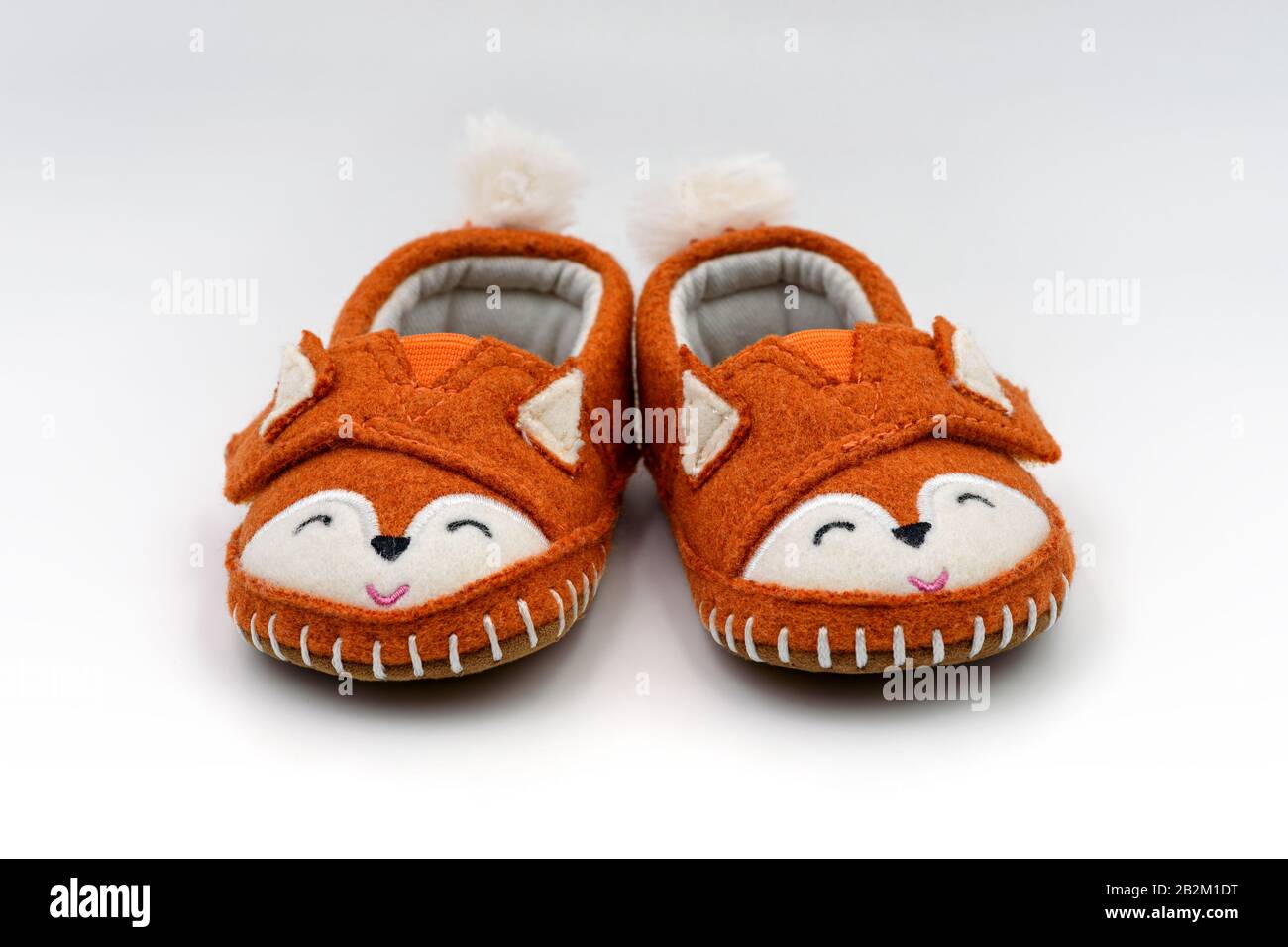 Cute orange fox shaped baby slippers isolated on white background. Stock Photo