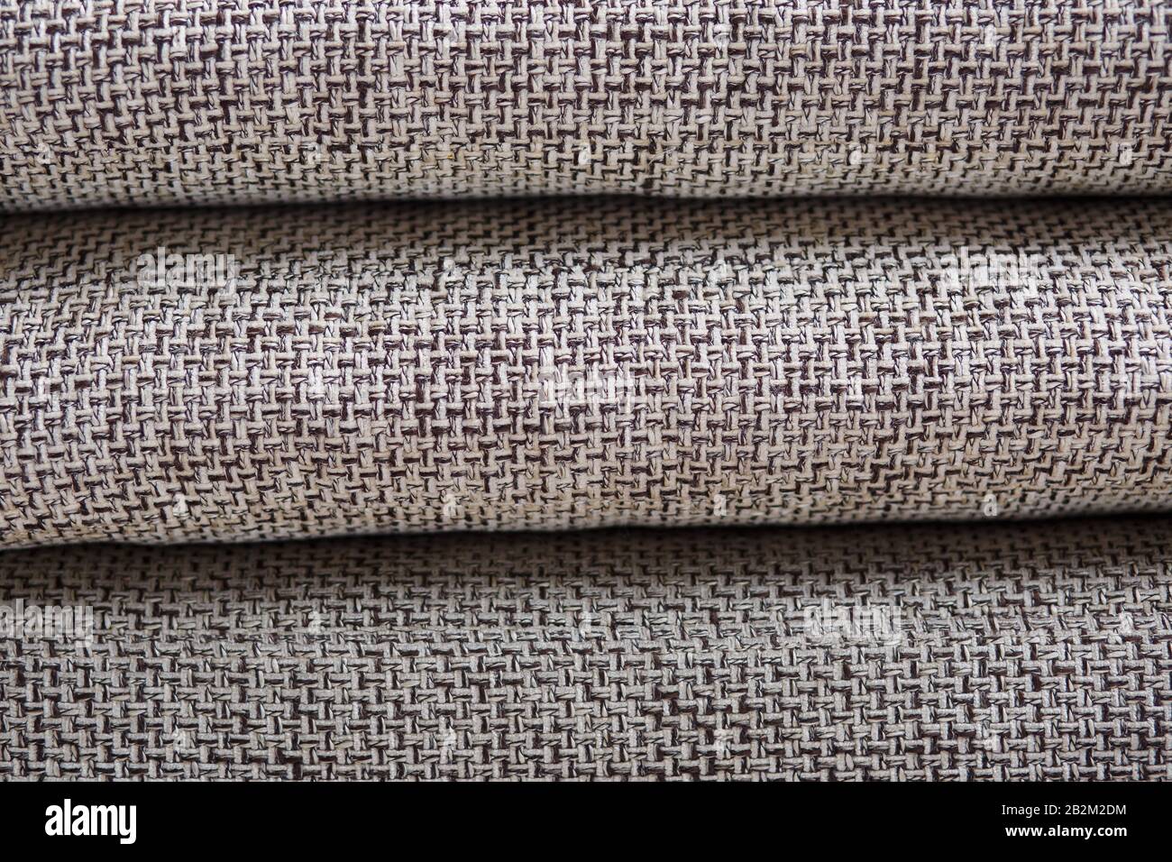 Closeup of a fragment of a beige textile sofa in the room. Texture of