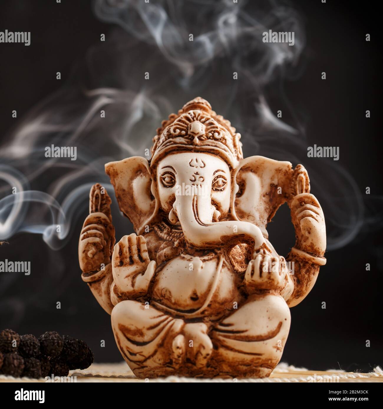 Hindu god Ganesh on a black background. Statue with incense smoke aromo  sticks. Copy space Stock Photo - Alamy