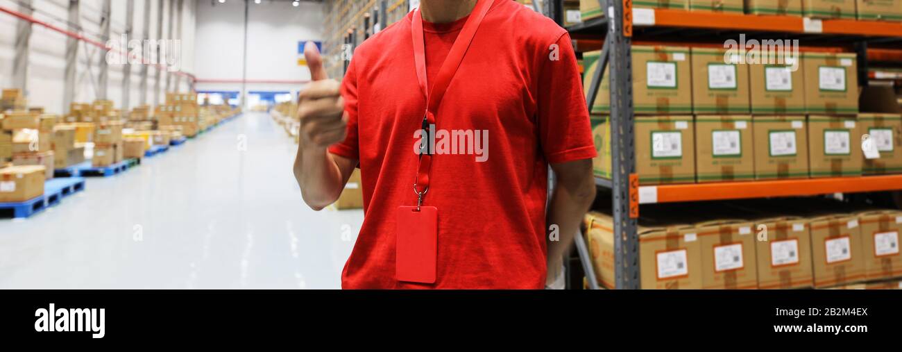 Logistics warehouse keeper in red tshirt against goods closeup Stock