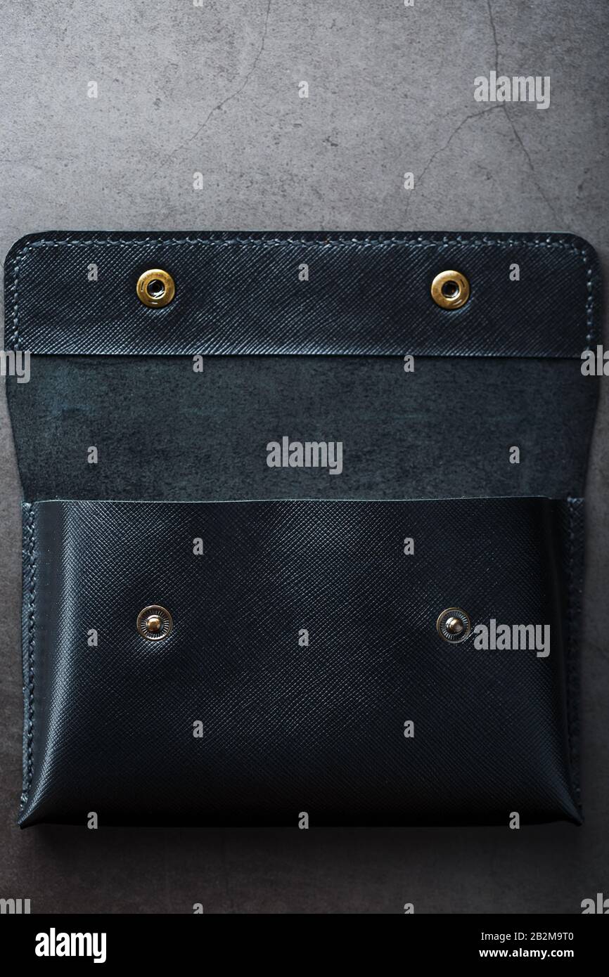 Black wallet made of genuine leather on a dark background. Handmade leather items. Rivets and seam close up Stock Photo
