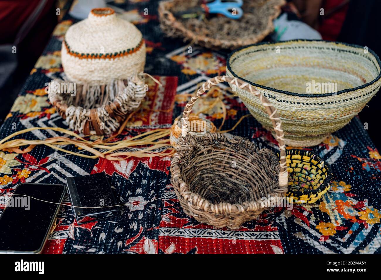 Different hand made weave basckets on table. Craft workshop. Close up shot. Stock Photo