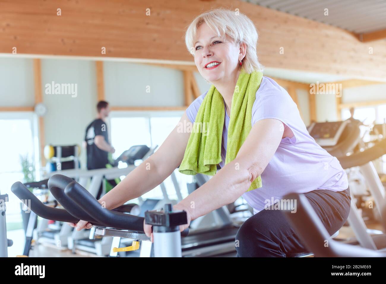 Senior woman exercising for better fitness on a bike in the gym Stock ...
