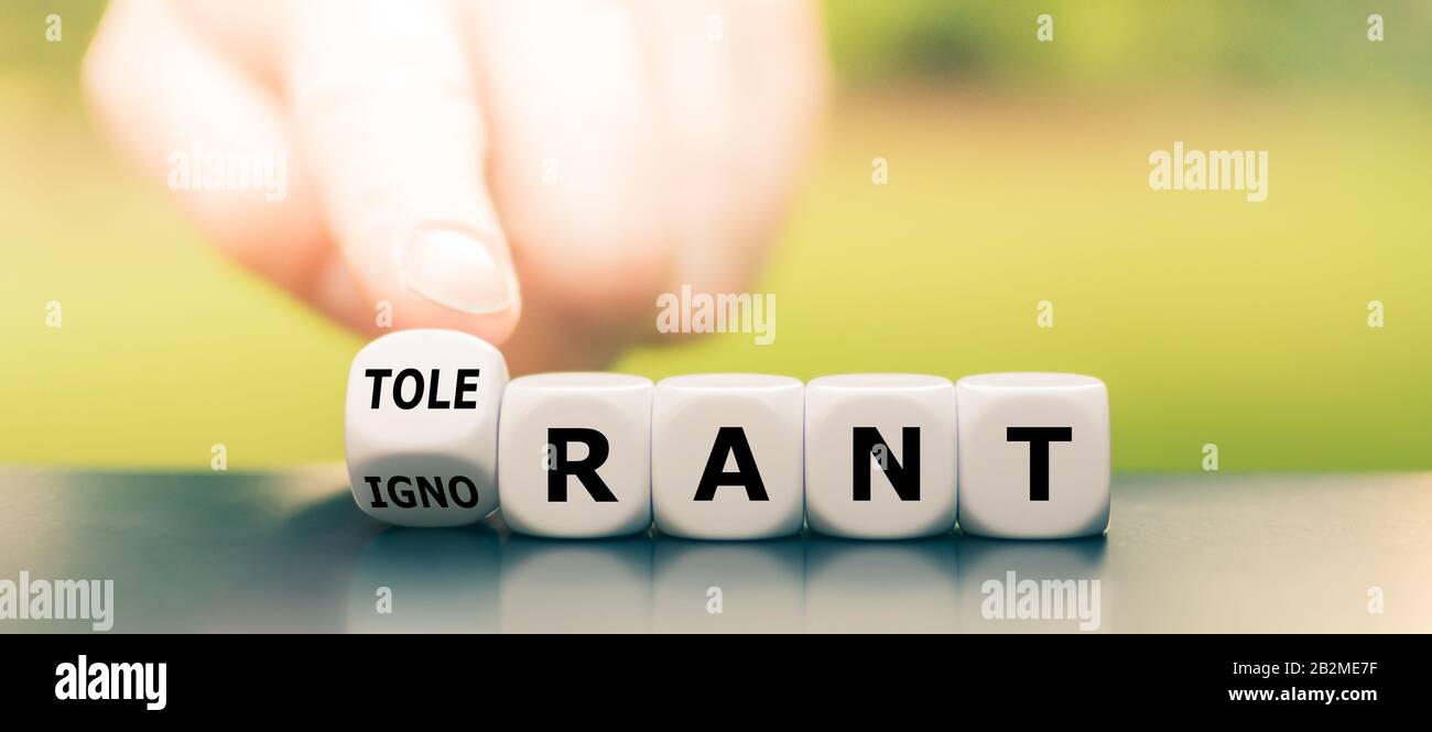 Ignorant or tolerant? Hand turns dice and changes the word 'ignorant' to 'tolerant'. Stock Photo