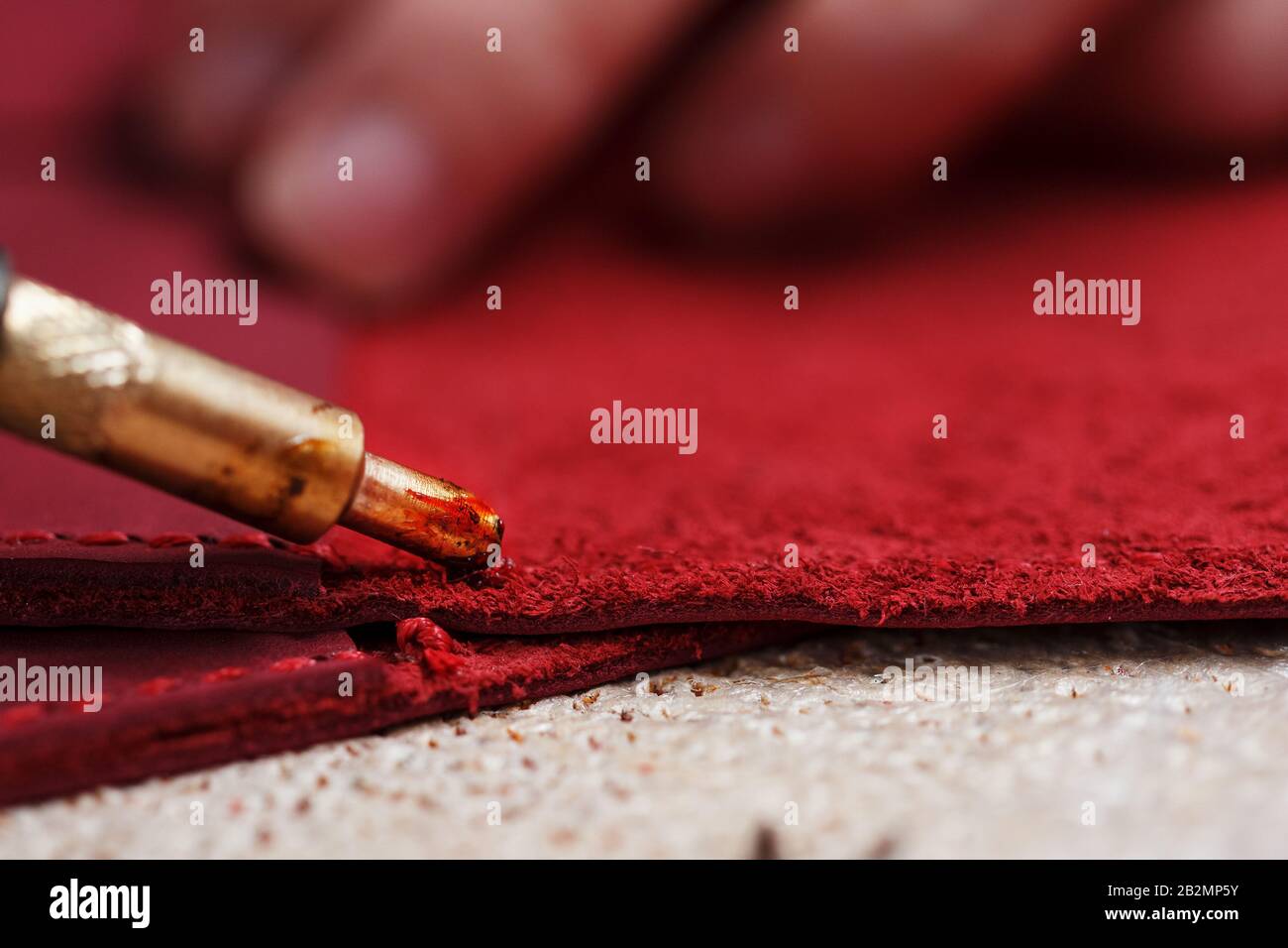 A leather craftsman works with leather. Sews leather goods. Making things handmade. Women's hands with a needle, thread, scissors and a blowtorch. Clo Stock Photo