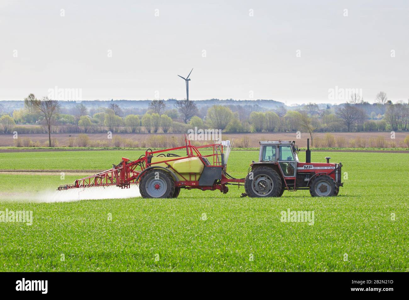 Farmer spraying pesticides / insecticides / weed killer / herbicide over field / farmland in spring Stock Photo