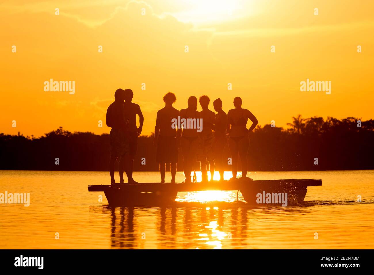 Group Of People On Laguna Grande Cuyabeno National Park In Ecuador Against Sunset Stock Photo