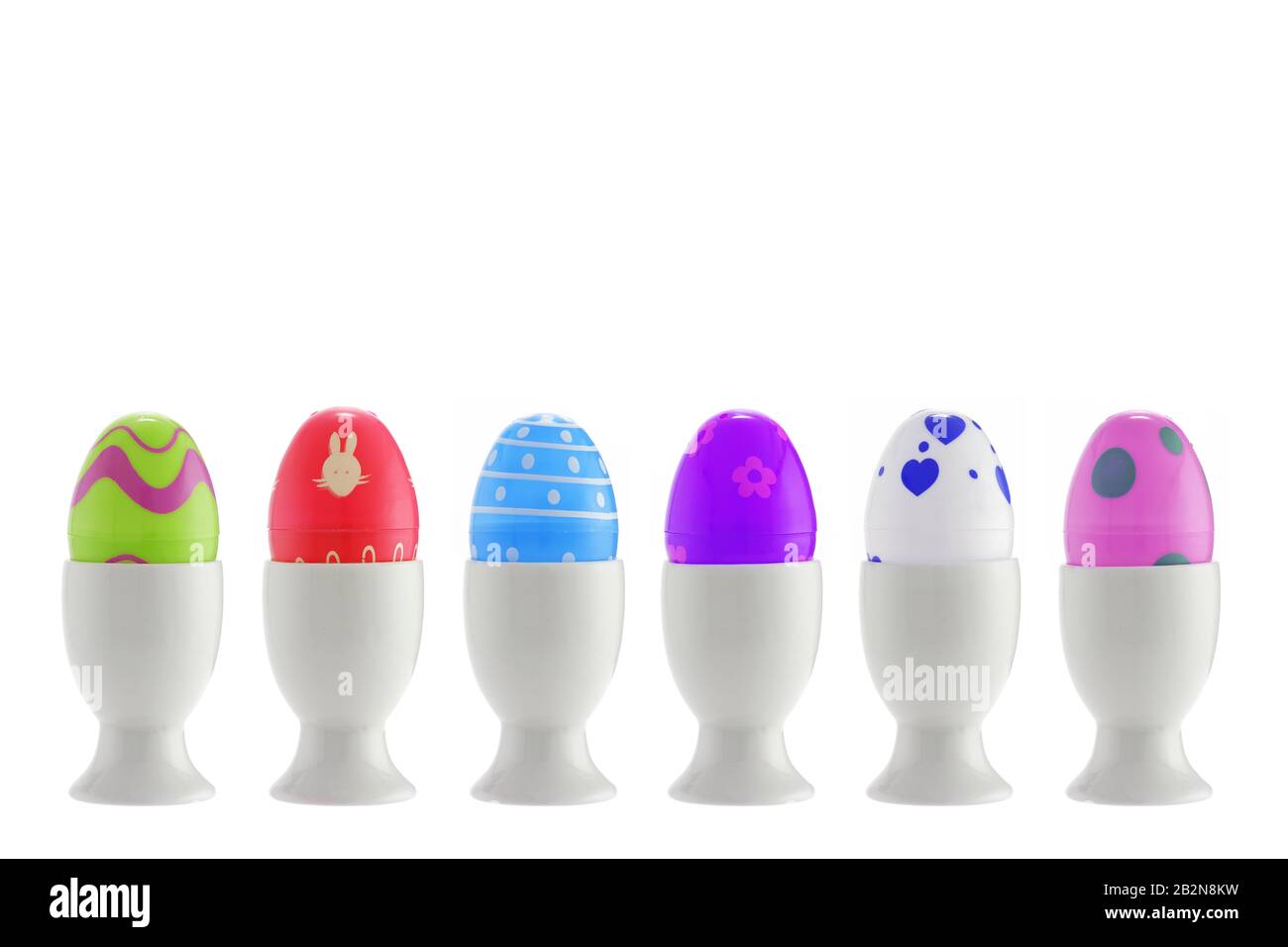 A set of six toy easter eggs in egg cups on white with clipping path Stock Photo
