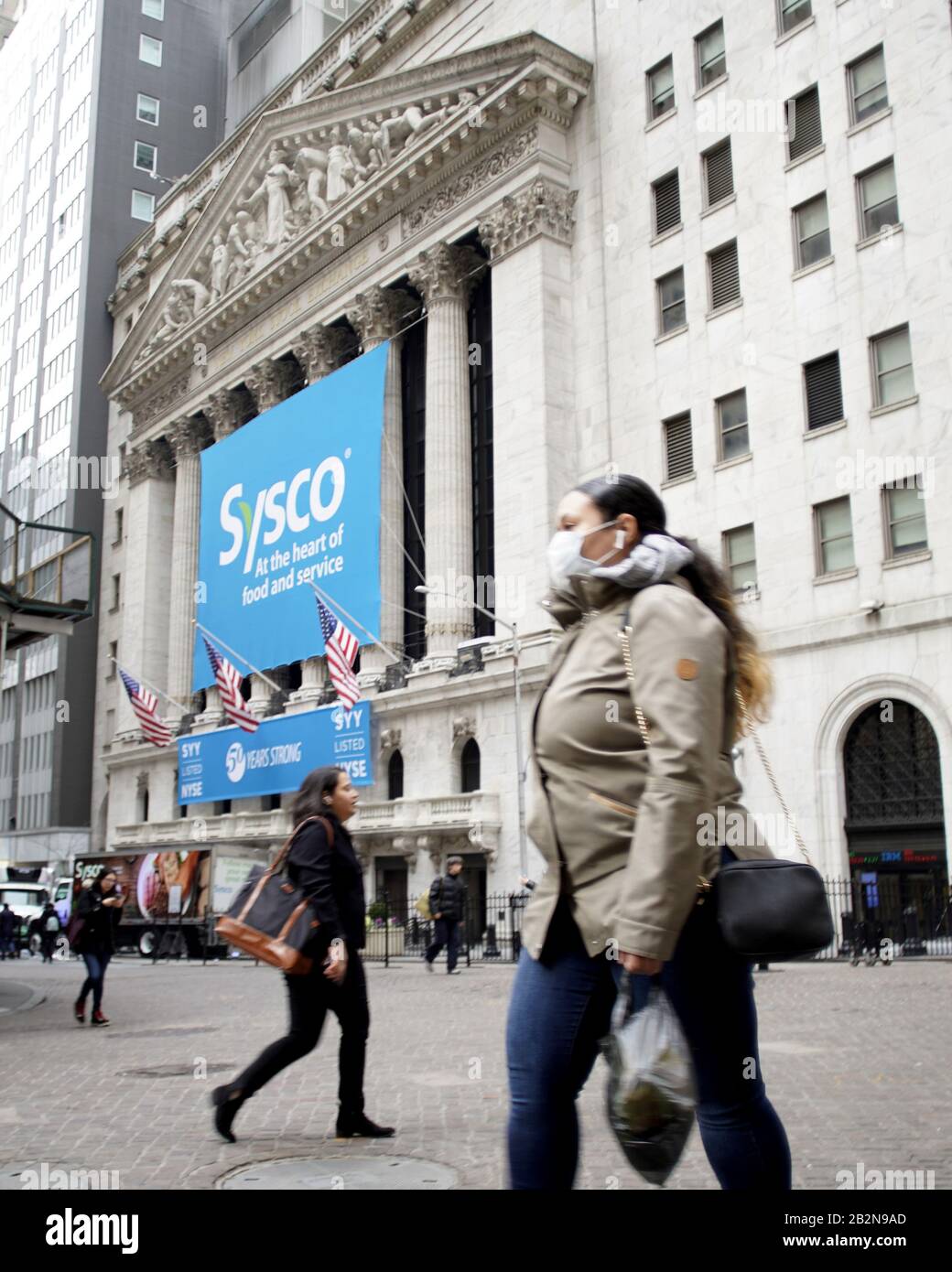New York, United States. 03rd Mar, 2020. A woman walks past the New York Stock Exchange wearing a face mask on Wall Street in New York City on Tuesday, March 3, 2020. The Fed cut rates by half a percentage point Tuesday to combat coronavirus slowdown. The number of coronavirus cases and deaths continues to climb in the U.S. Photo by John Angelillo/UPI Credit: UPI/Alamy Live News Stock Photo