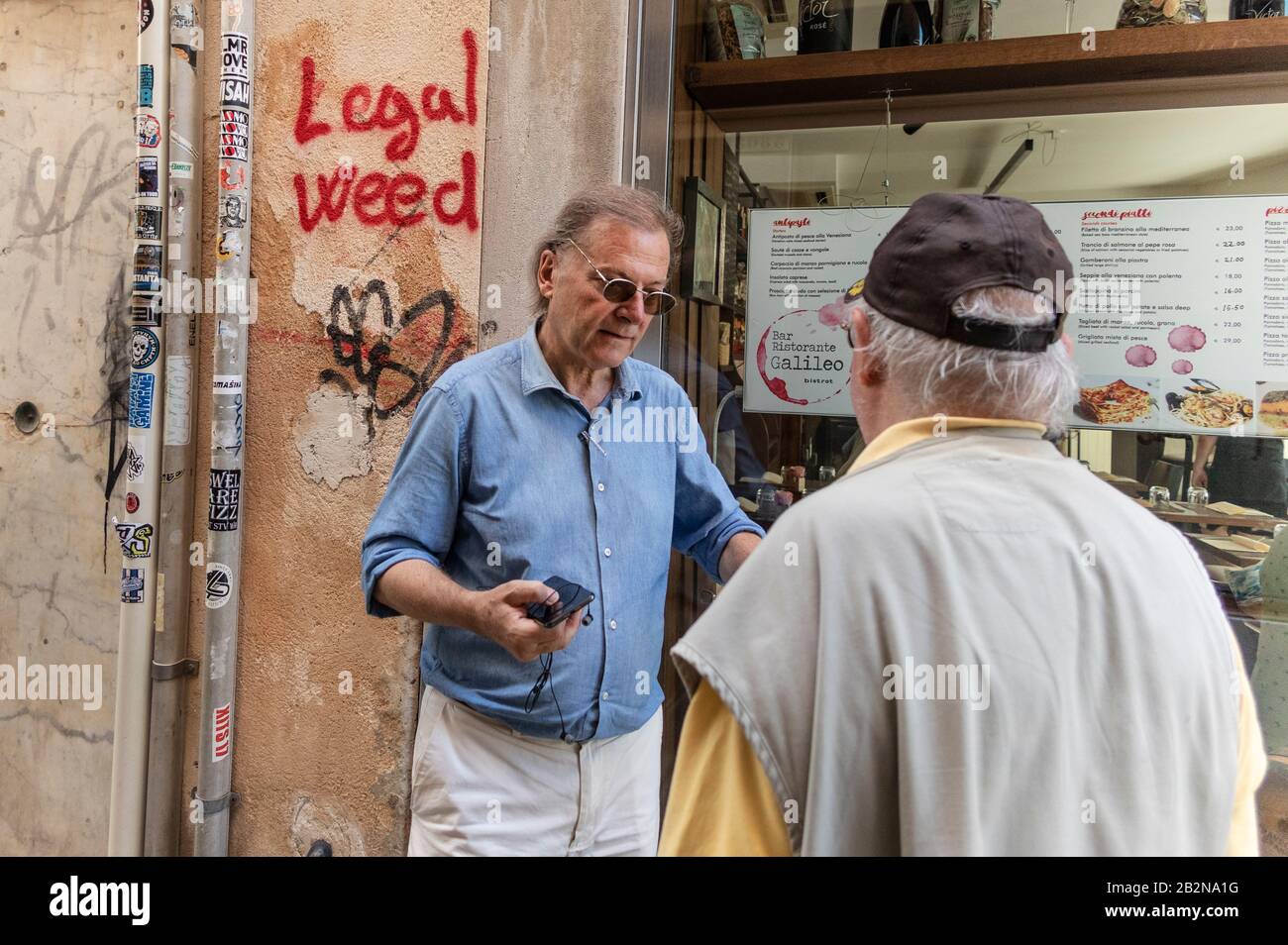 Locals talking in the street with 'legalise weed' graffiti in ...