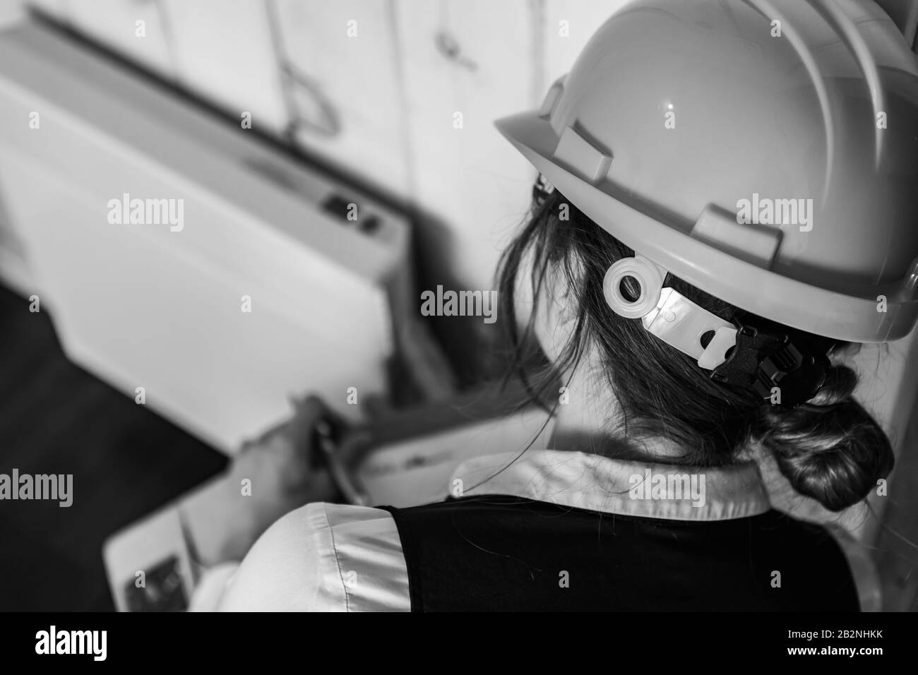close up and selective focus, rear view of inspector woman, inspecting a modern eco energy efficient house. black and white with copy space. Stock Photo