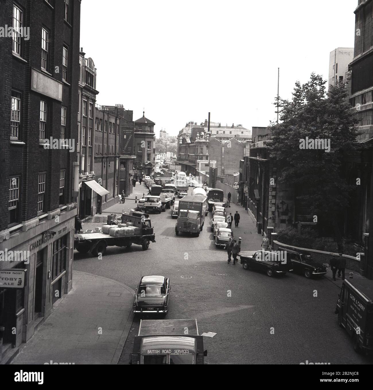 1960s, historical, a view down Thames Street, City of London, showing vehicles of the day, delivery trucks and a Charrington's pub, selling Toby Ales, England, UK. Divided into Lower and Upper Thames Street goes along the River Thames from Westminster to Tower Hill. Stock Photo