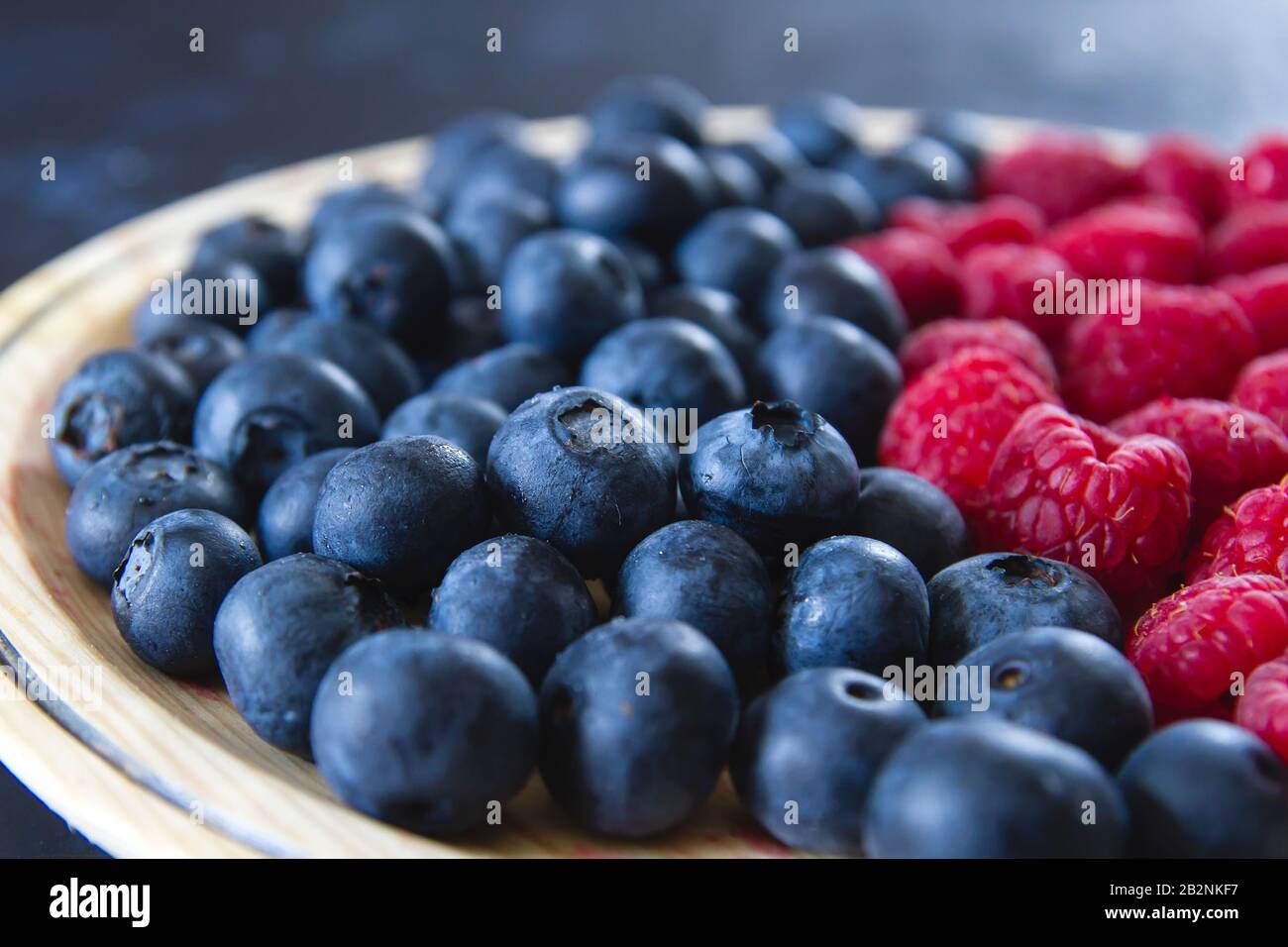 Fresh blueberries and raspberries on wooden dish Stock Photo
