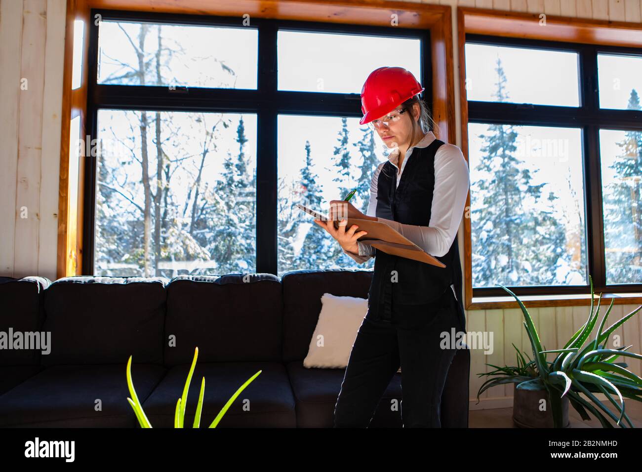 home inspector woman wearing red hard hat takes professional notes on