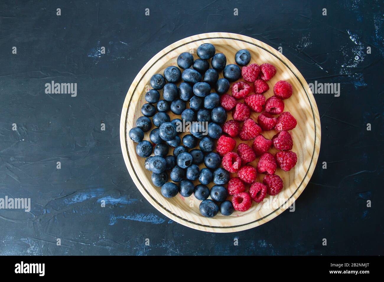 Fresh blueberries and raspberries on wooden dish Stock Photo