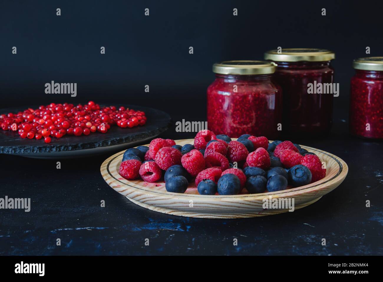 Homemade jam with fresh blueberries, raspberries and redcurrants, dark backdrop Stock Photo