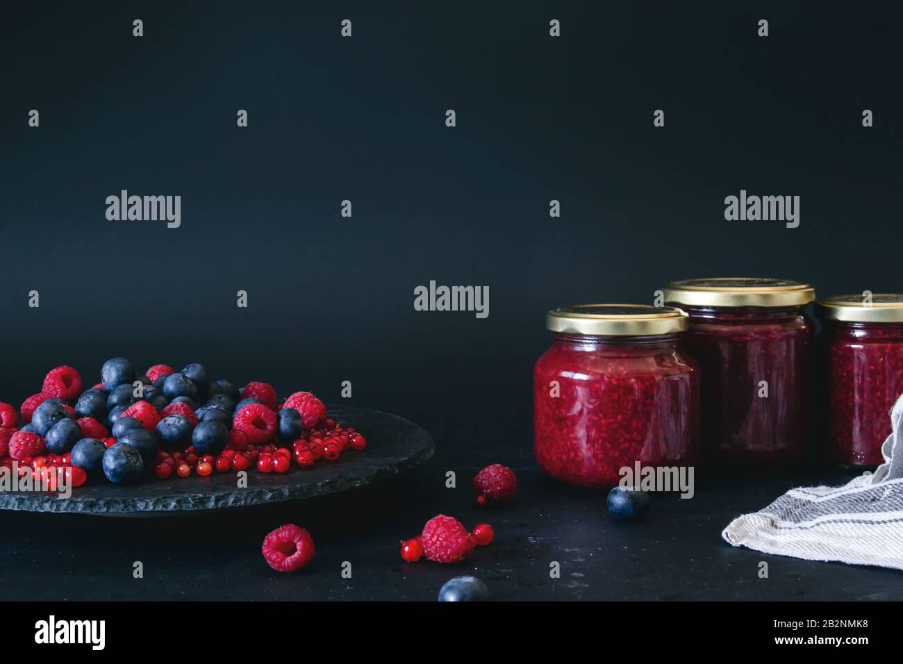 Homemade jam with fresh blueberries, raspberries and redcurrants, dark backdrop Stock Photo