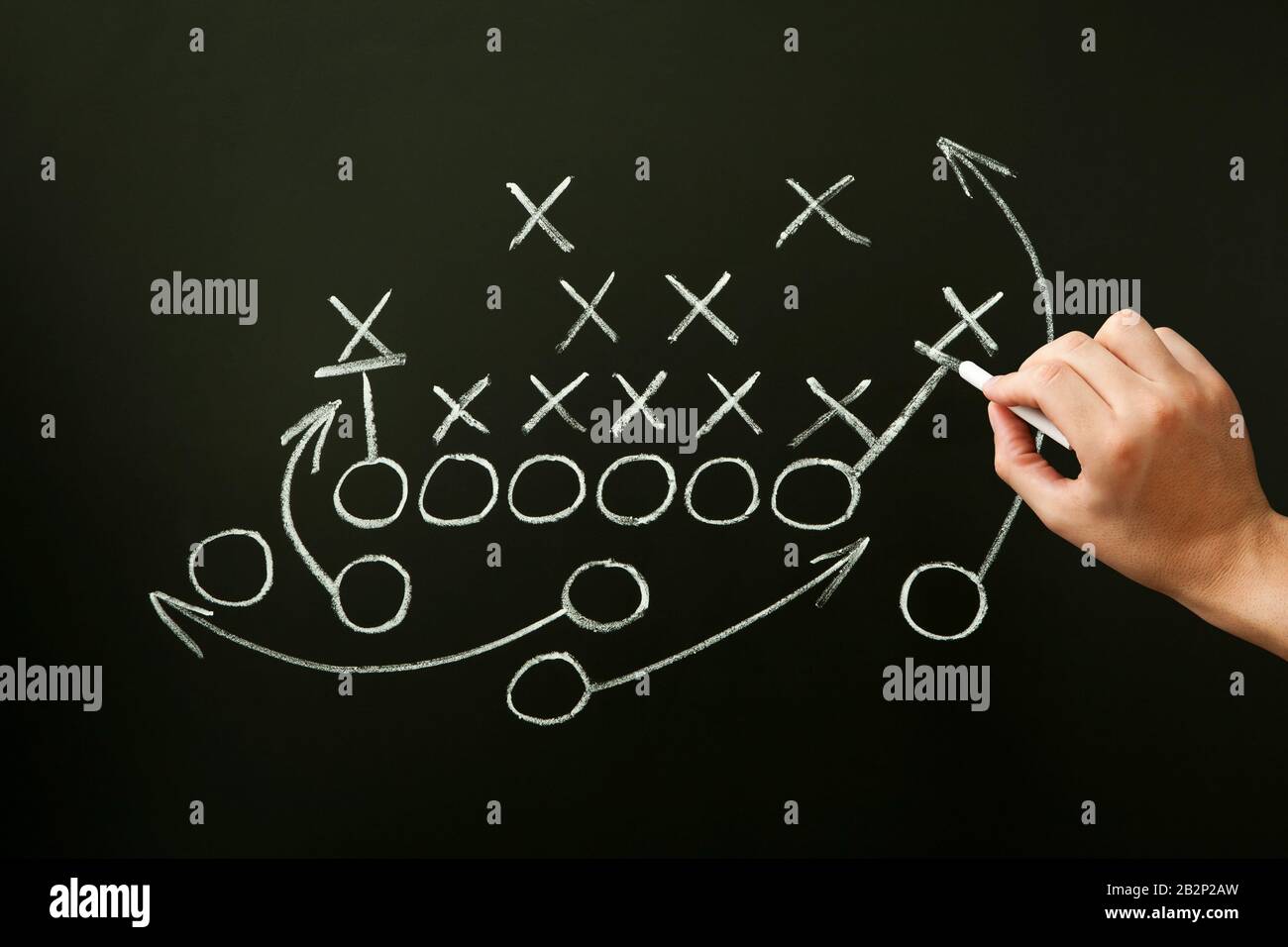 Coach drawing american football or rugby game playbook, strategy and tactics with chalk on blackboard. Stock Photo