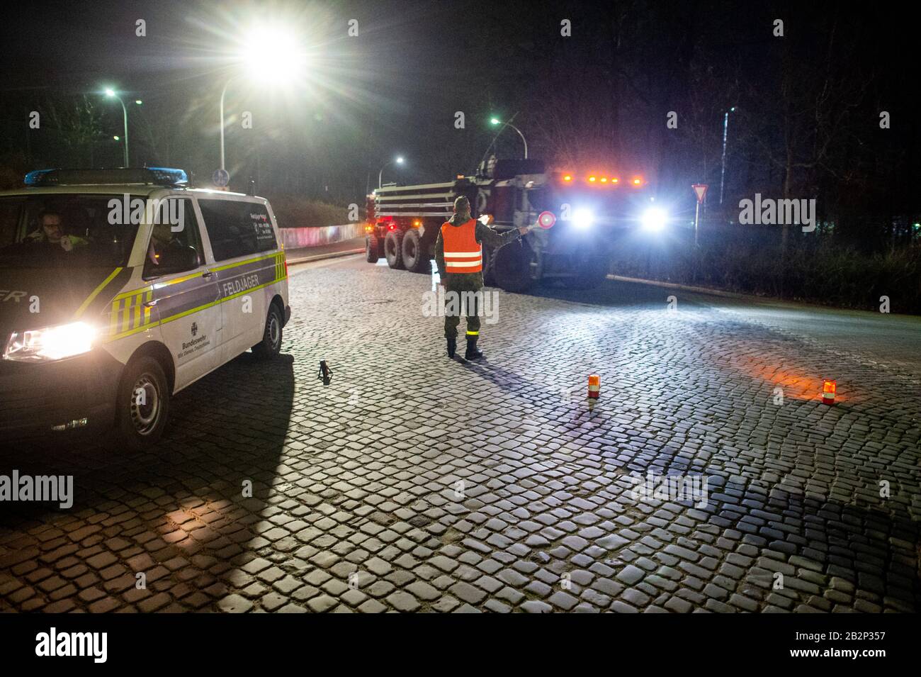 03 March 2020, Saxony-Anhalt, Burg: A soldier of Logistics Battalion 171 instructs US Army vehicles to enter the gate of Clausewitz Barracks. The military vehicle will be transferred from a depot in Belgium to Poland for the US-led exercise 'Defender Europe 2020'. On their way through Saxony-Anhalt the military convoys stop at the Clausewitz barracks to refuel. Around 37,000 soldiers from 18 nations will participate in the exercise. In the coming weeks, the US military is moving around 1,500 vehicles to Poland, which are to be refuelled in the Clausewitz barracks. Photo: Klaus-Dietmar Gabbert/ Stock Photo