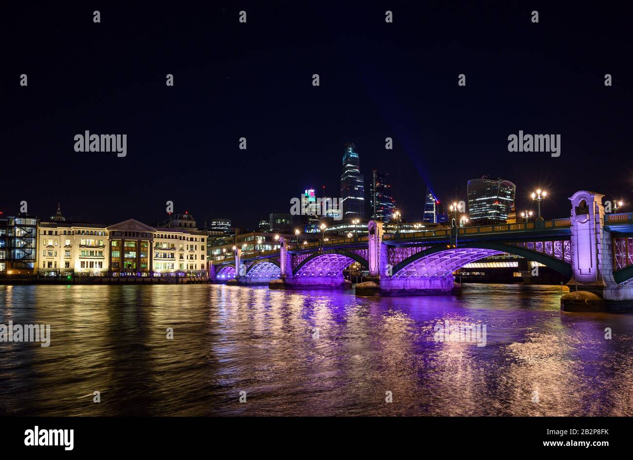 City of London, UK with view over the River Thames and Southwark Bridge at night. Cityscape with skyscrapers, lights, and dark sky. London 2020. Stock Photo