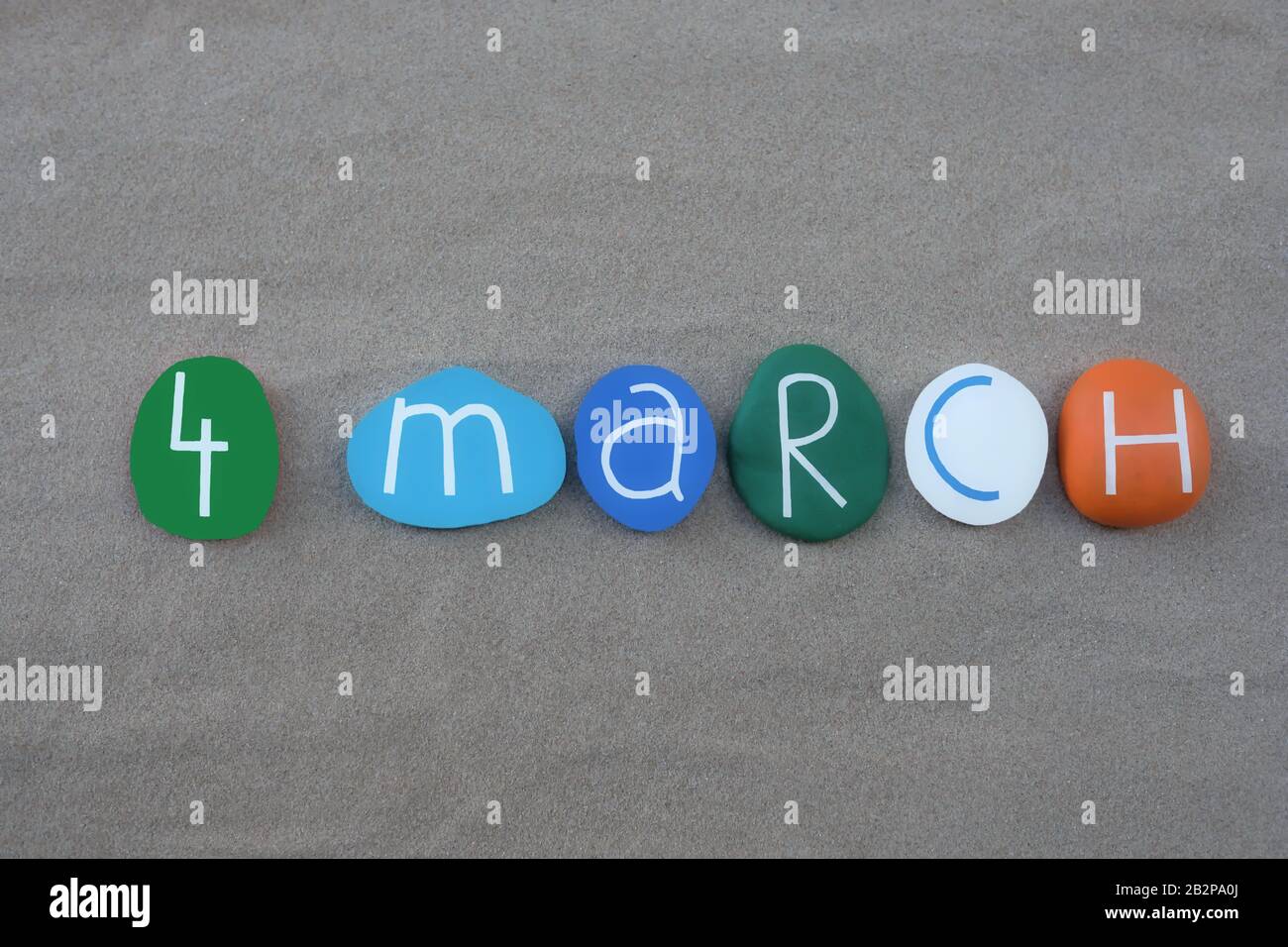 4 March, calendar date composed with colored and carved stones over green sand Stock Photo