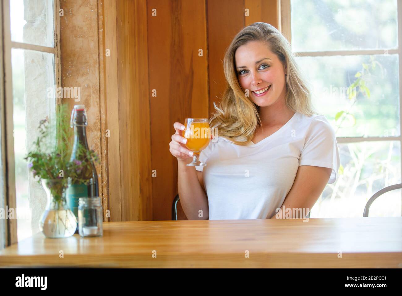 A person enjoying local brewery fresh craft beer in a tulip glass, gorgeous wooden background with window light Stock Photo