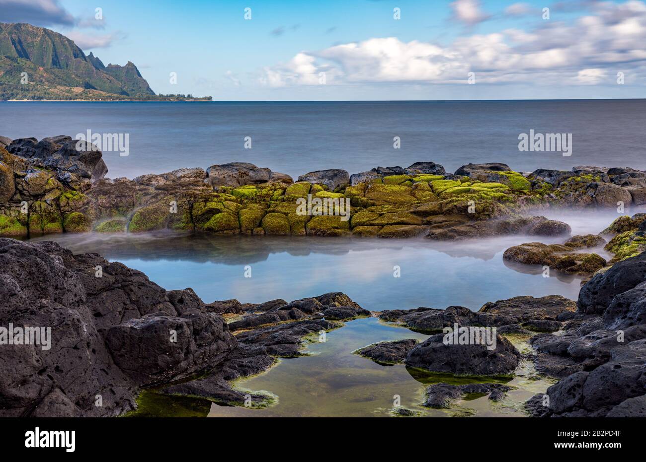 Long exposure of the calm waters of Queen's Bath, a rock pool off Princeville on north shore of Kauai Stock Photo